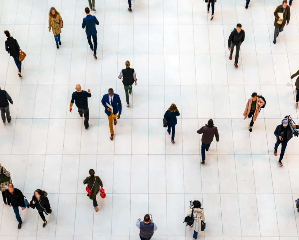 aerial image of people walking in opposite ways on a white tile floored atrium 